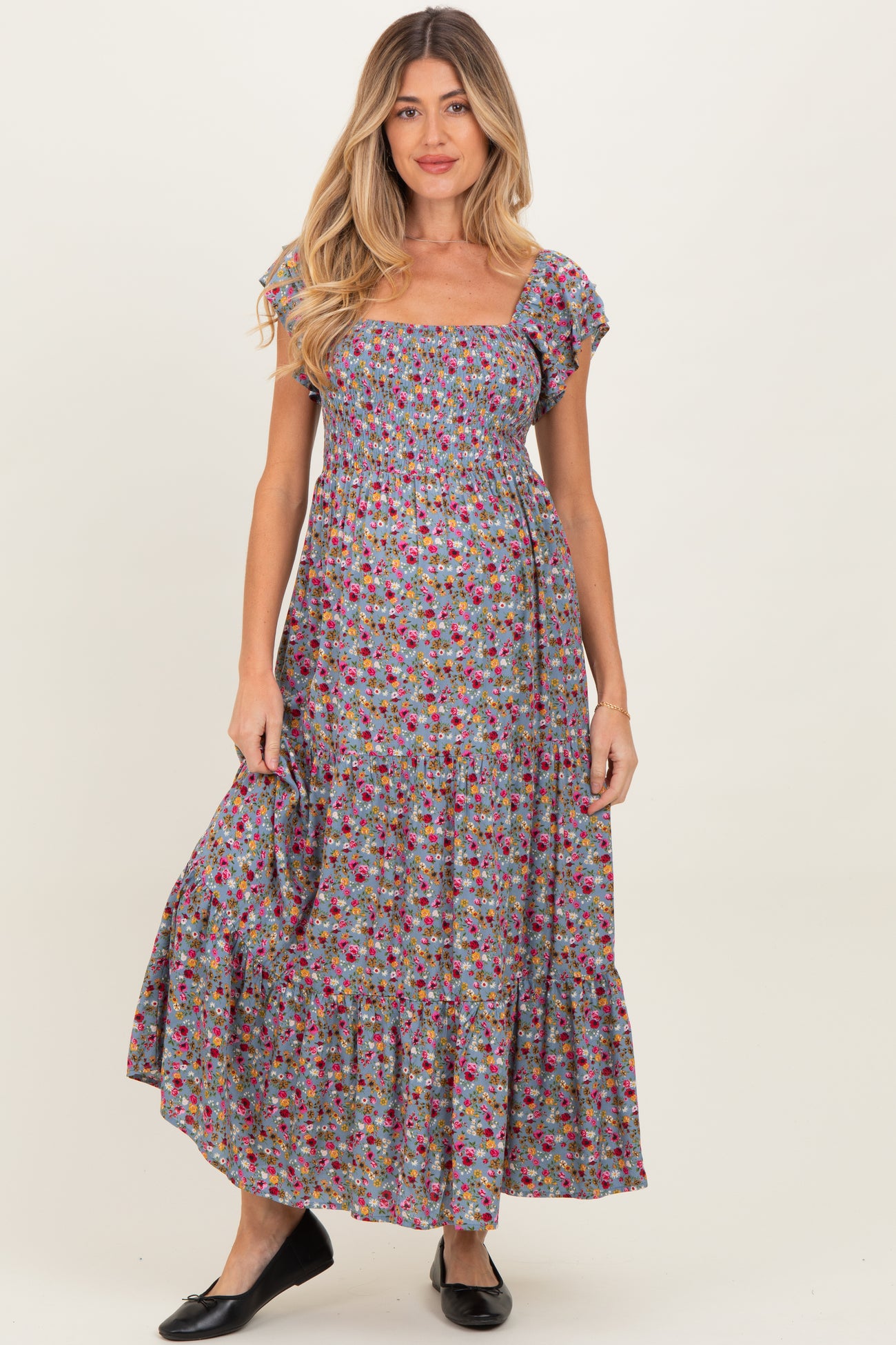 woman wearing a floral maternity maxi dress with short ruffle sleeves and a smocked bodice, featuring a tiered skirt
