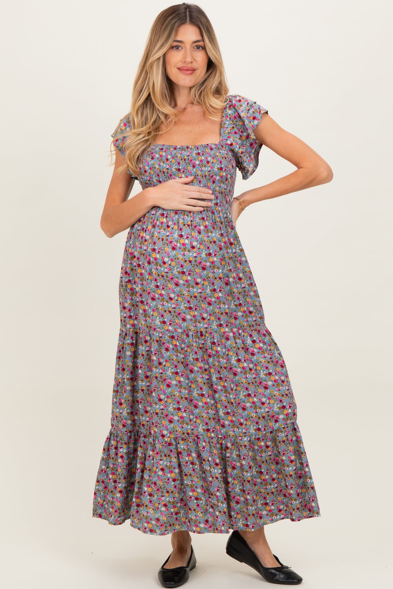 woman wearing a floral printed maternity maxi dress and holding her baby bump