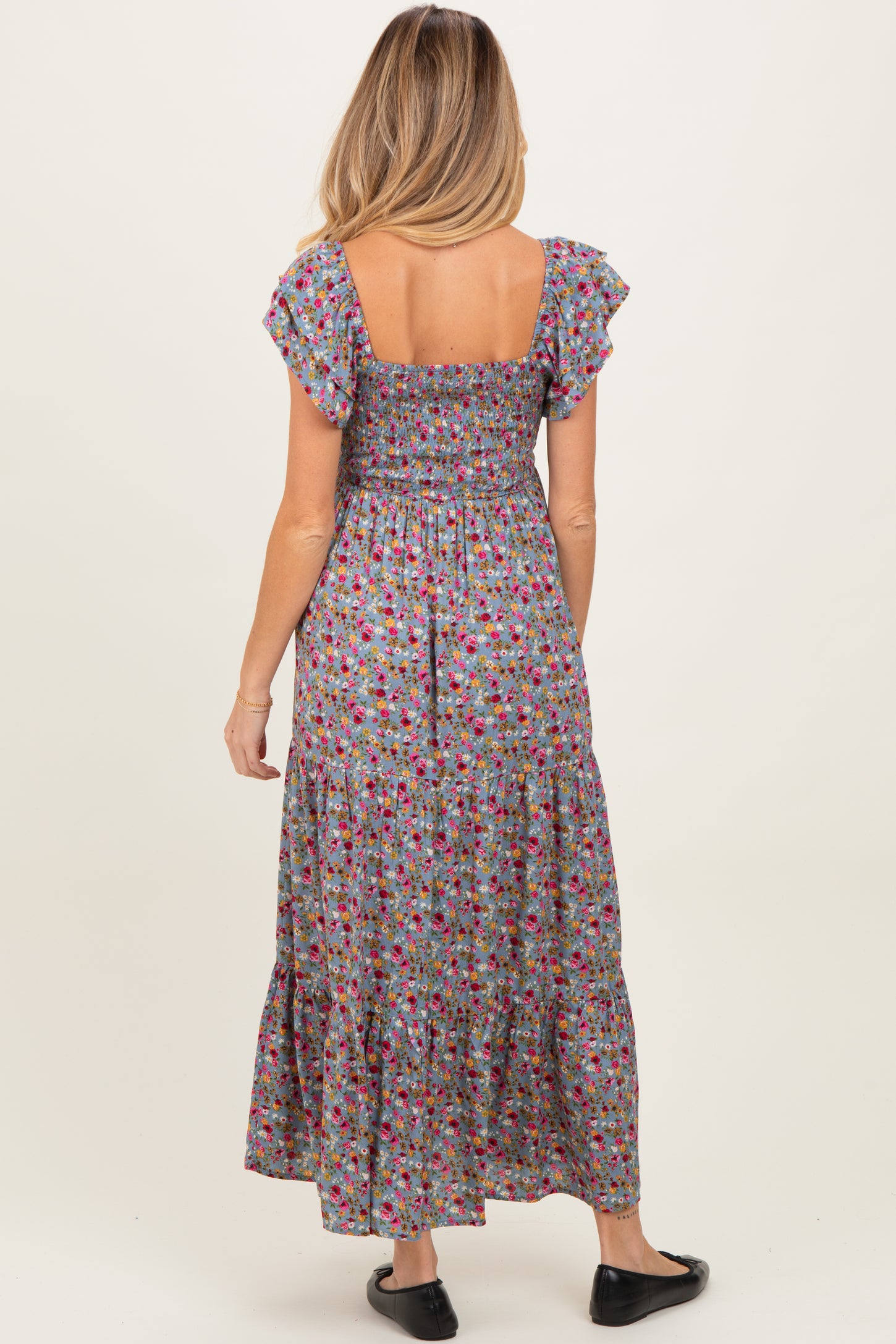 woman wearing a floral print maternity maxi dress with short ruffle sleeves and a smocked bodice
