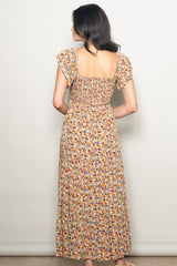 woman wearing a brown floral maxi dress with a smocked back and ruffled sleeves, shown from the back