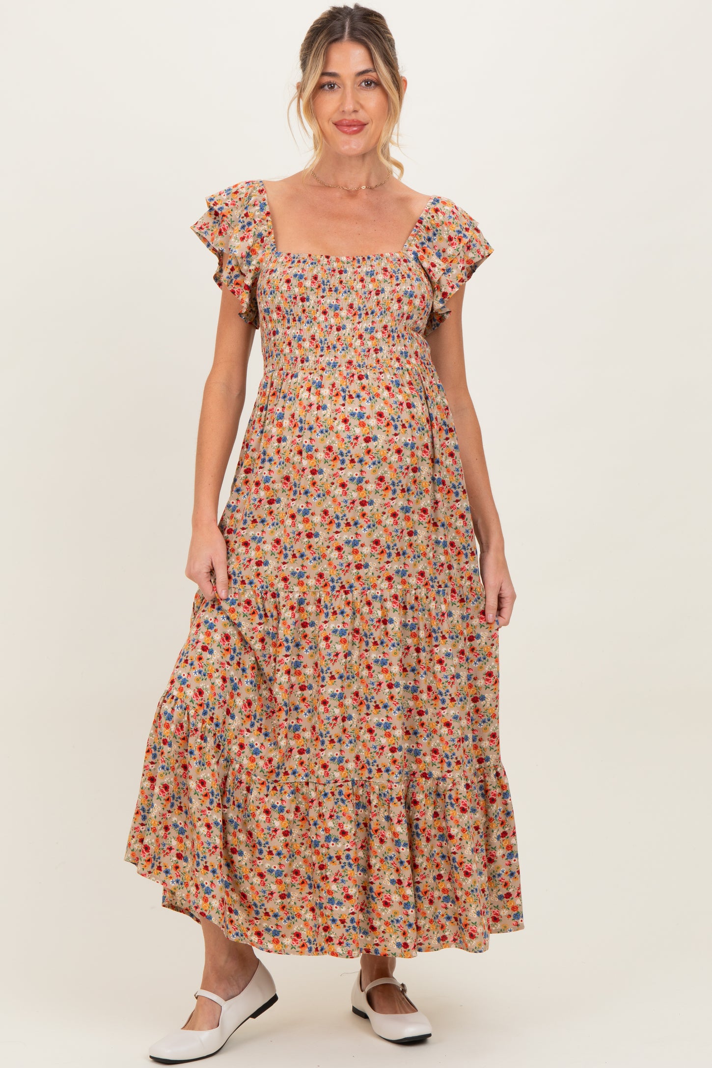 woman wearing a floral print maternity maxi dress with ruffle sleeves and a smocked bodice, showcasing her baby bump