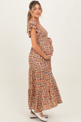 woman wearing a floral maternity maxi dress with ruffled sleeves and cradling her baby bump