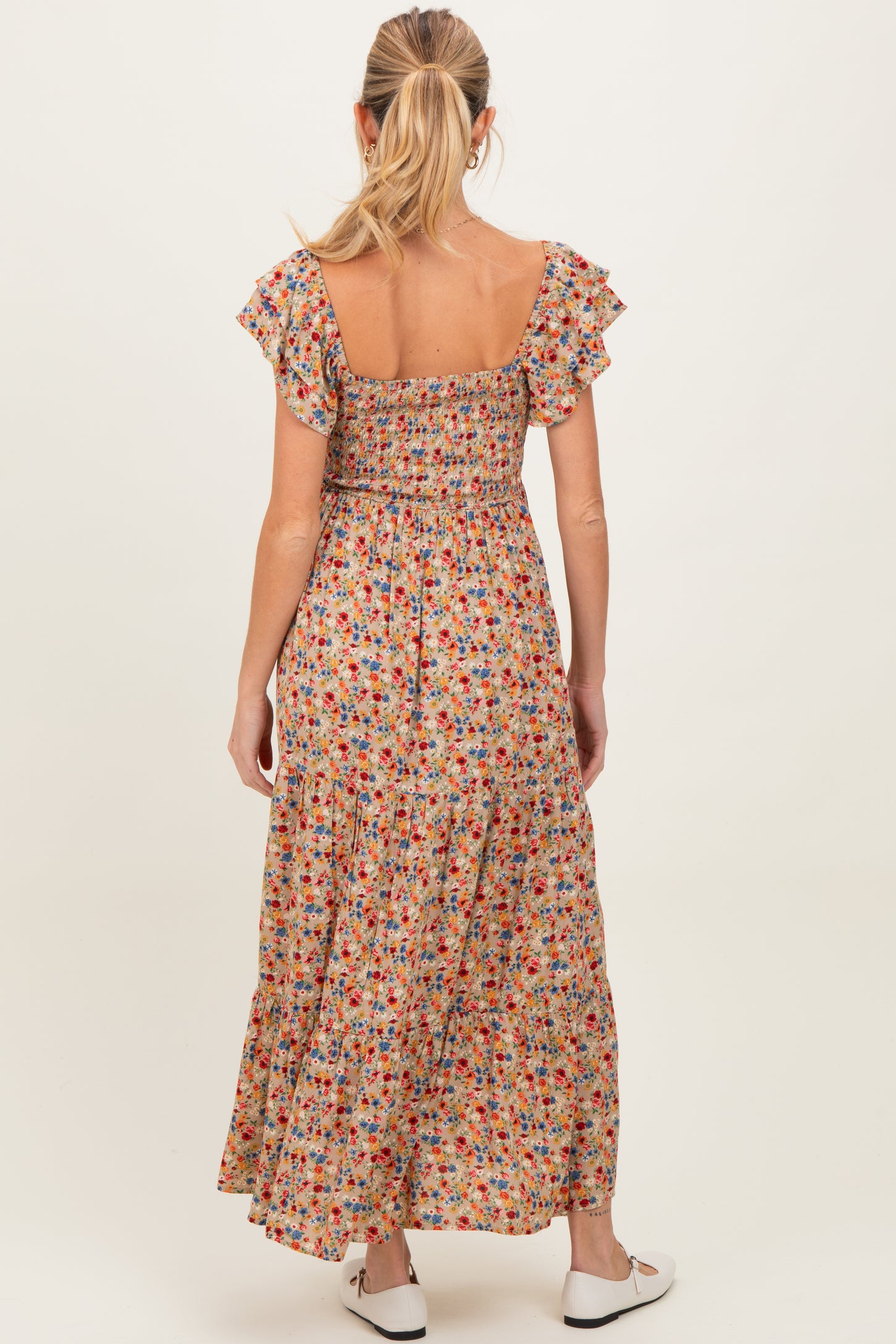 woman wearing a floral maternity maxi dress with ruffled sleeves and a smocked back detail, showing her baby bump