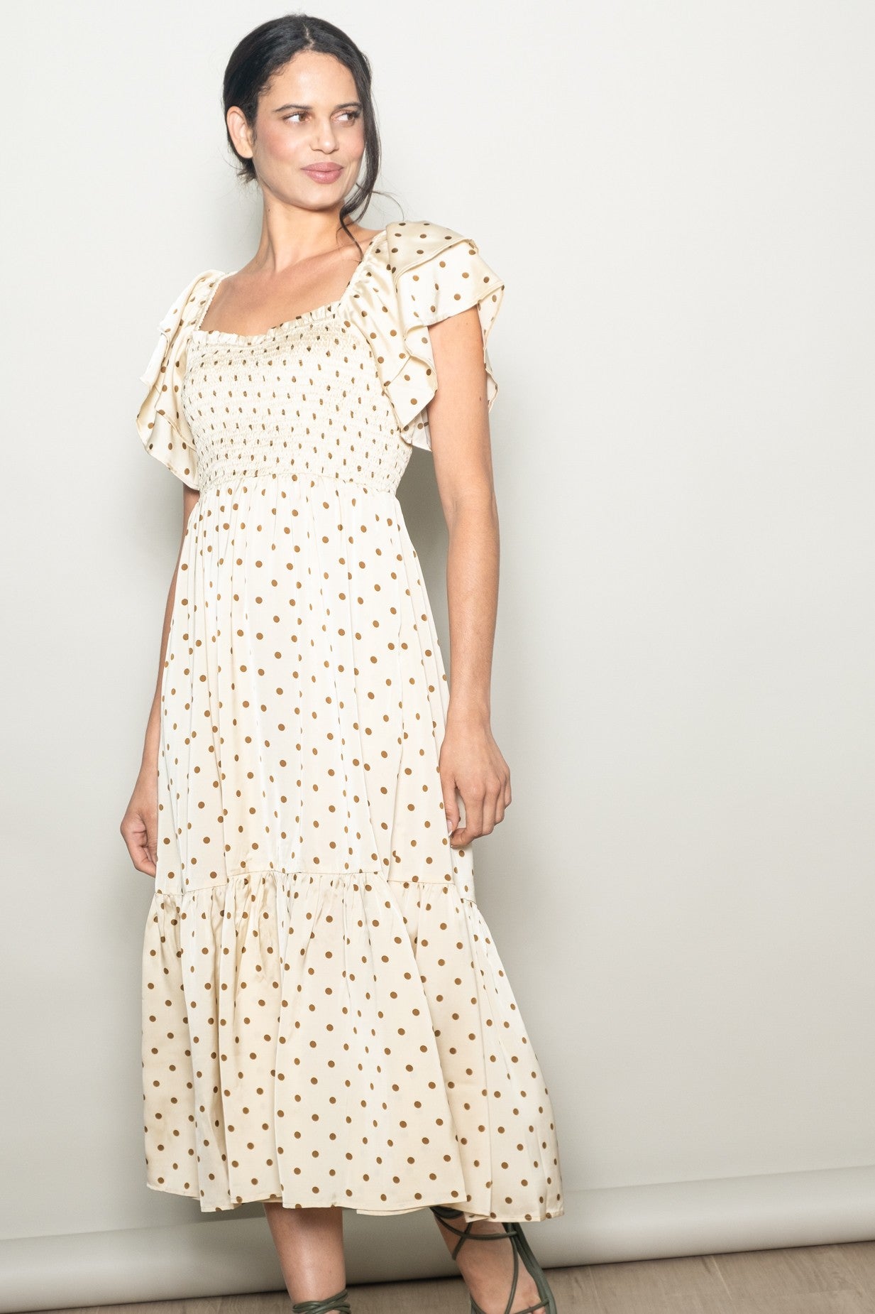 woman wearing a cream polka dot midi dress with ruffled sleeves and a smocked bodice