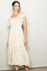 woman wearing a cream polka dot midi dress with ruffled sleeves and a smocked bodice