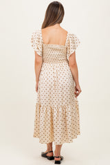 woman wearing a cream polka dot maternity maxi dress with a smocked bodice and flutter sleeves, shown from the back