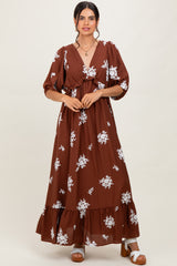 woman wearing a brown floral maxi dress with a v-neckline and puff sleeves, standing with hands on her hips