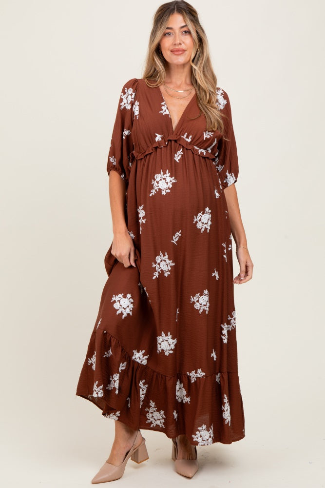 woman wearing a brown floral print maternity maxi dress with a tie detail and a visible baby bump