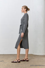woman wearing a gray striped long sleeve midi dress with a side slit and a waist tie