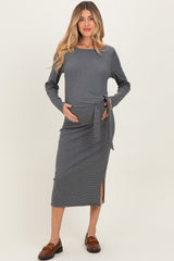 woman wearing a navy and white striped maternity dress with a tie detail and side slit, holding her baby bump