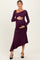 woman wearing a dark purple long sleeve maternity dress with an asymmetrical hem and holding her baby bump