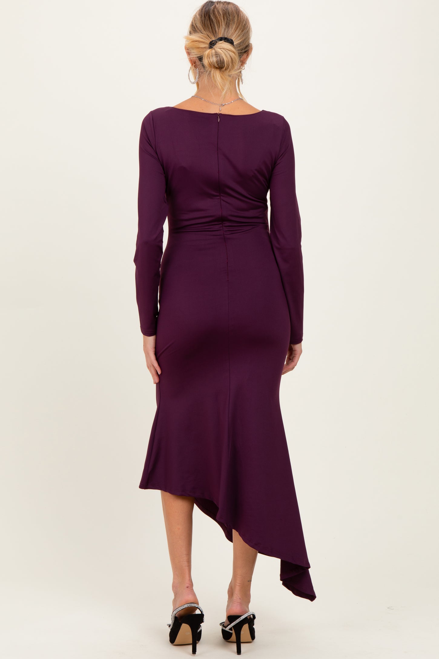 woman wearing a purple long sleeve maternity dress with an asymmetrical hemline, viewed from the back