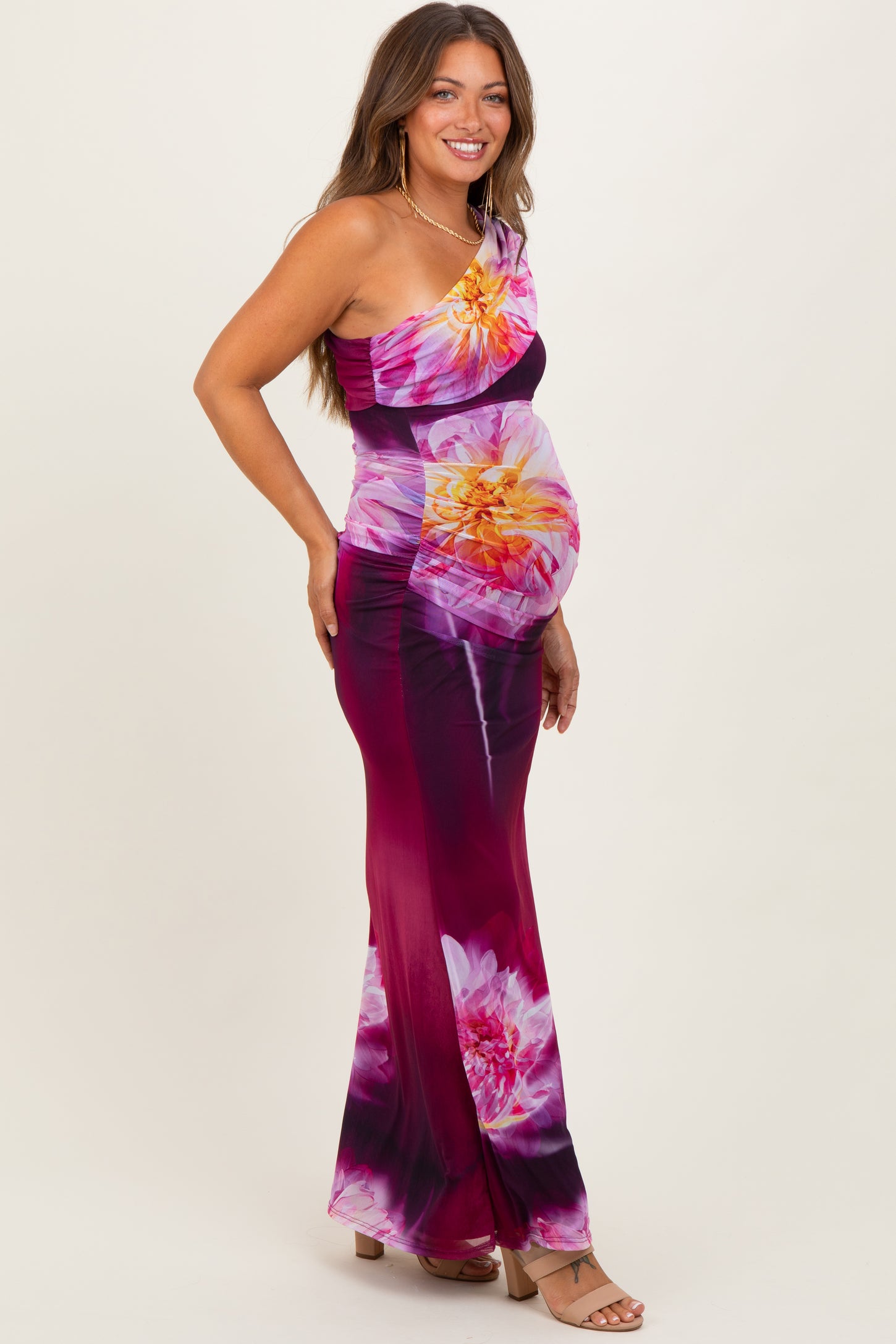 woman wearing a colorful floral print one-shoulder maternity dress showing her baby bump