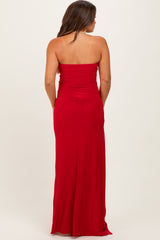 woman wearing a red strapless maternity gown with a fitted silhouette and a long flowing skirt, showing her back