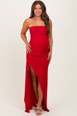 woman wearing a red strapless maternity dress with a side slit, showcasing her baby bump