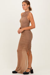 woman wearing a tan sleeveless ruched dress with a side slit and a high neckline
