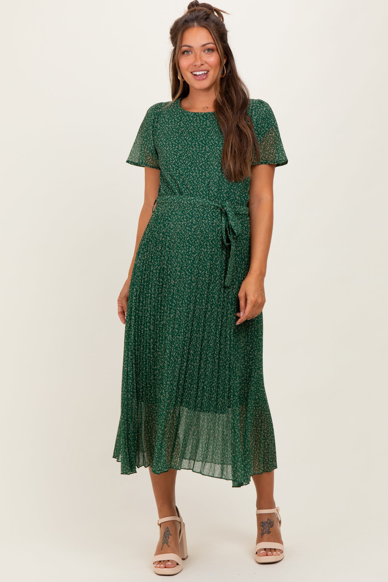 woman wearing a green floral maternity dress with short sleeves and a tied waist detail