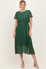 woman wearing a green floral midi dress with short sleeves and a tie waist, styled with nude heels and layered necklaces