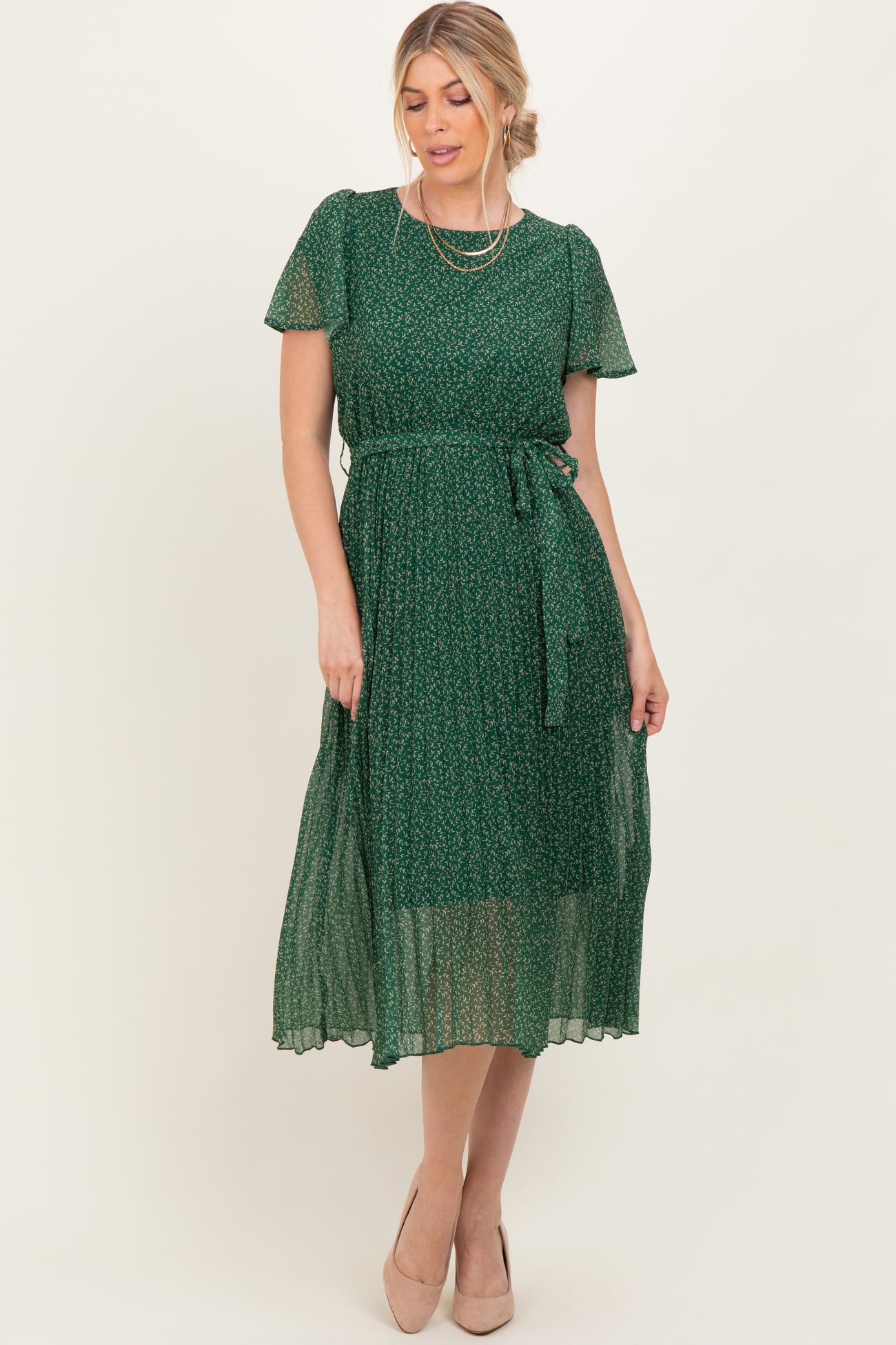 woman wearing a green floral midi dress with short sleeves and a tie waist, posing elegantly