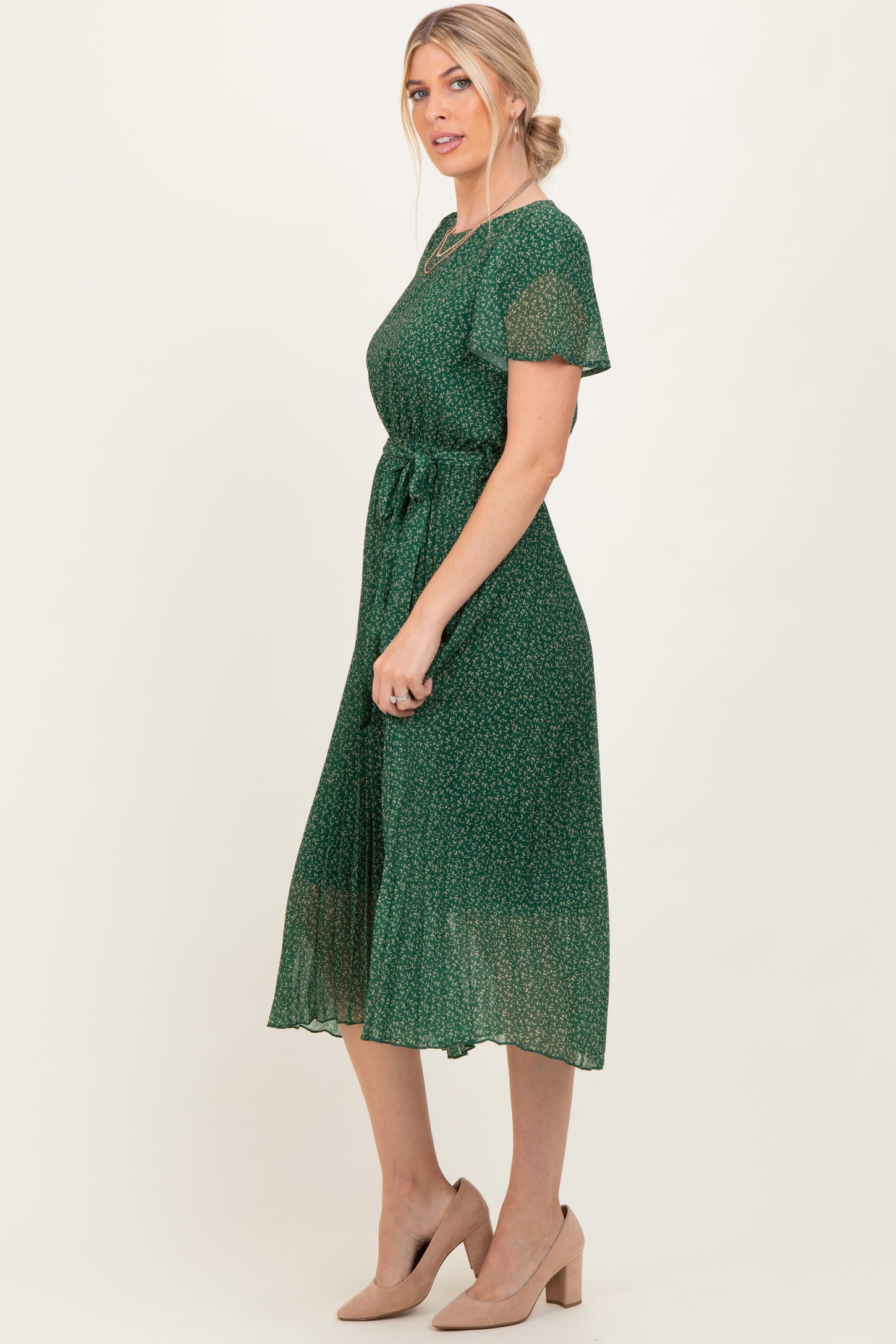 woman wearing a green floral midi dress with short sleeves and a tie waist, styled with beige heels