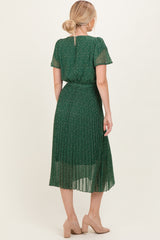 woman wearing a green floral pleated midi dress with short sleeves and a tie waist detail