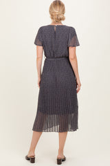 woman wearing a navy blue pleated dress with short sleeves and a cinched waist, viewed from the back