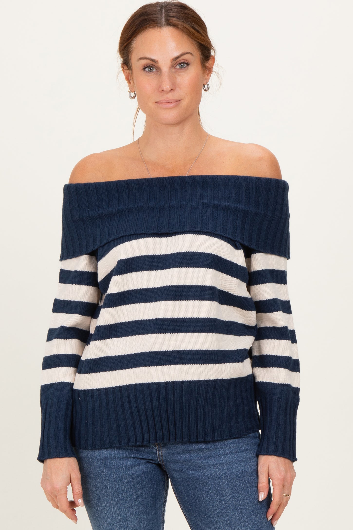 woman wearing a navy and white striped off-the-shoulder sweater paired with blue jeans