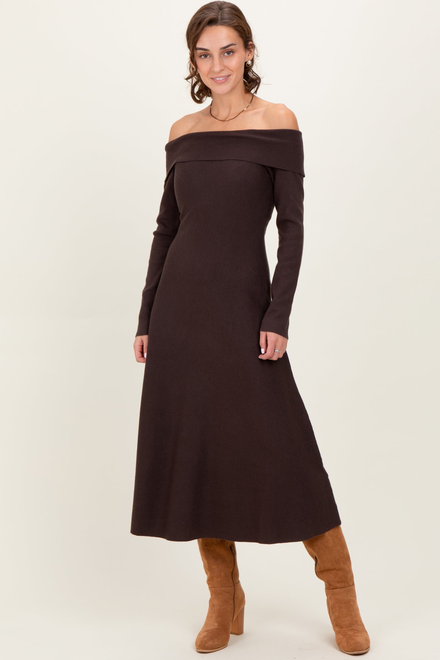 woman wearing a brown off-the-shoulder knit maxi dress and tan knee-high boots