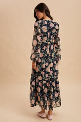 woman wearing a black floral maxi dress with long sleeves and a relaxed fit, standing with her back to the camera