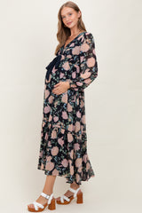 woman wearing a floral maternity dress with a deep v-neck and ruffle hem, holding her baby bump