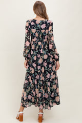 woman wearing a long sleeve black floral maternity maxi dress with ruffles and a baby bump visible from the back