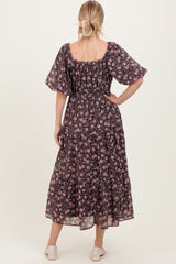 woman wearing a black floral maxi dress with short flutter sleeves and a tiered skirt, viewed from the back