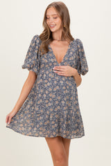 woman wearing a floral print maternity dress with puff sleeves and a v-neck, holding her baby bump