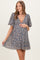woman wearing a floral print maternity dress with puff sleeves and a v-neck, holding her baby bump
