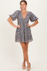 woman wearing a blue floral short dress with puff sleeves and a V-neckline, posing in a studio setting