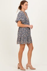 woman wearing a blue floral short sleeve dress with a ruffled hem and beige heels