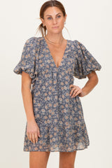woman wearing a blue floral printed short dress with puff sleeves and a deep v-neckline