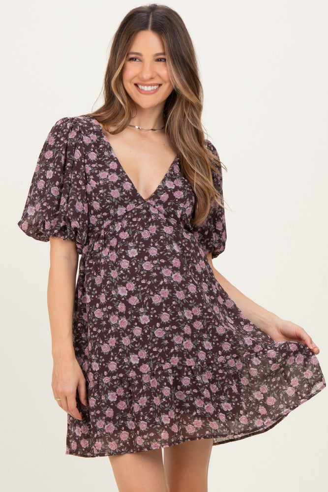 woman wearing a dark floral maternity dress with puff sleeves and a v-neckline, showing her baby bump