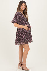 woman wearing a black floral maternity dress with short sleeves and a visible baby bump