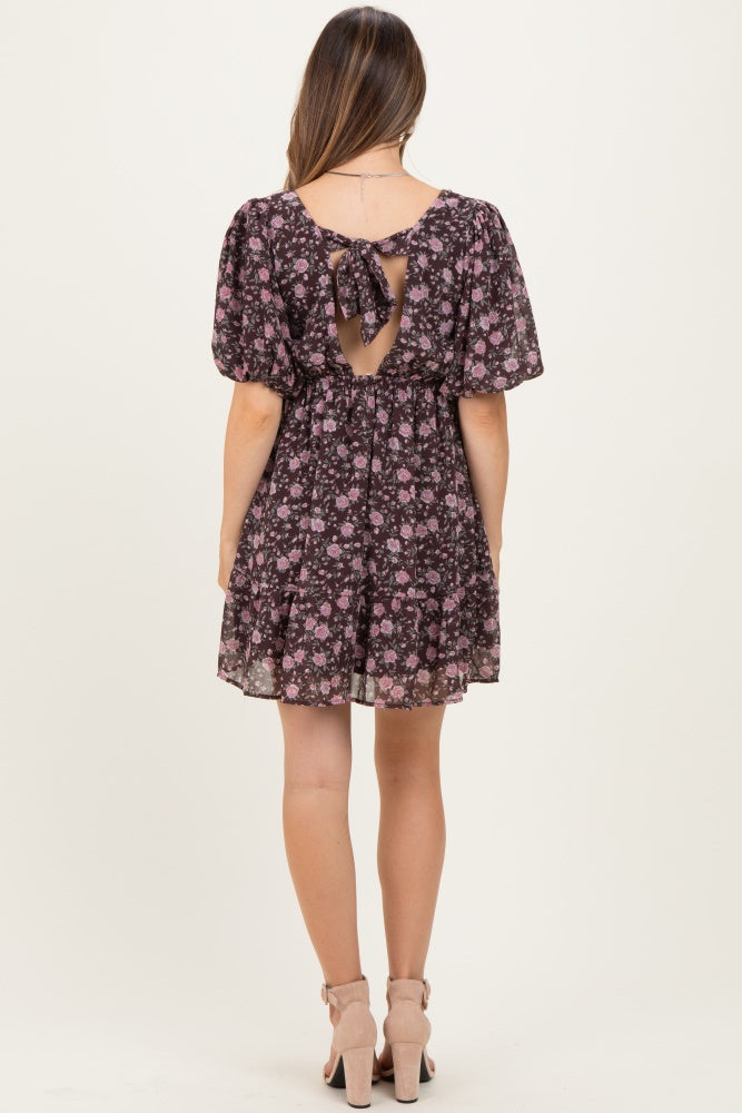 woman wearing a black floral maternity dress with a keyhole back and short puff sleeves