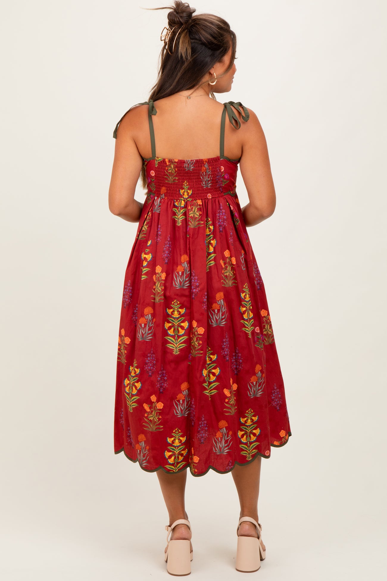 woman wearing a red floral maternity dress with tie straps and a loose fit, showing a baby bump in the back view