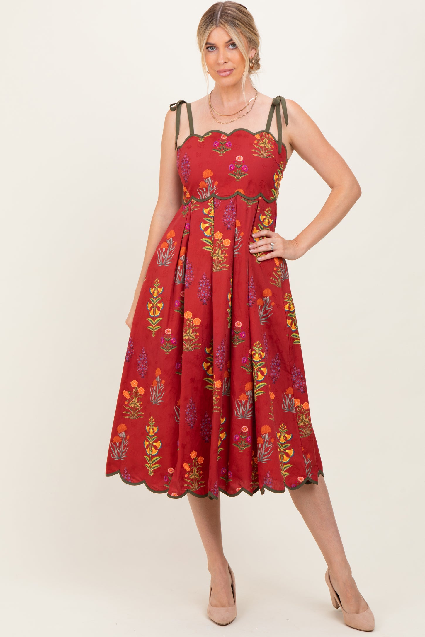 woman wearing a red floral midi dress with scalloped neckline and adjustable straps, posing confidently