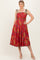 woman wearing a red floral midi dress with scalloped neckline and adjustable straps, posing confidently