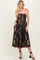 woman wearing a black floral print midi dress with spaghetti straps and scalloped hem, styled with sandals