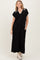 woman wearing a black maxi dress with a white collar and pockets, styled with cream ankle boots