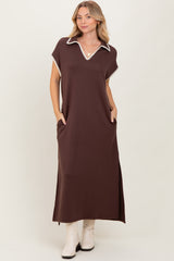 woman wearing a brown maxi dress with a white collar and pockets, standing against a neutral background