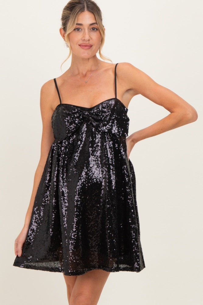 woman wearing a black sequin maternity dress with a twisted front detail and adjustable straps, highlighting a baby bump