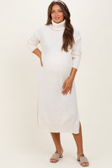 woman wearing a cream knitted maternity sweater dress with a turtleneck and side slits, showing her baby bump