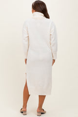 woman wearing a cream-colored maternity sweater dress with a turtleneck and side slits