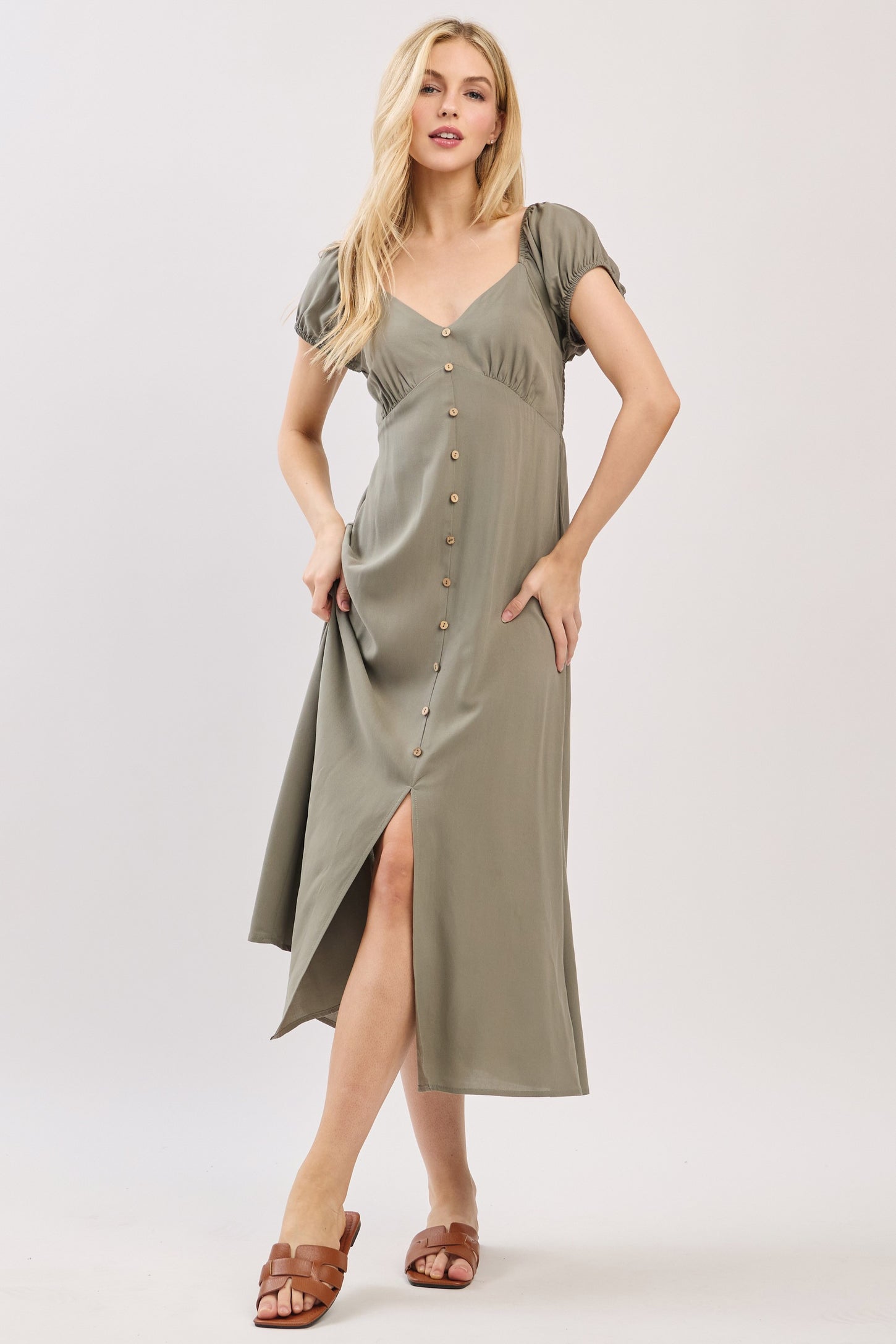 woman wearing a green button-up midi dress with short puff sleeves and a high slit
